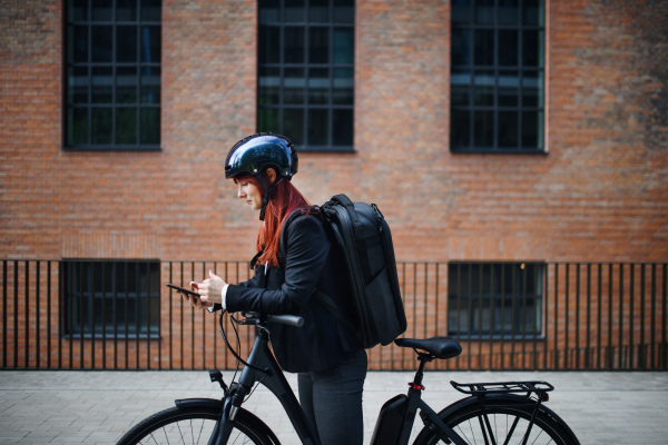 A portrait of businesswoman commuter on the way to work with bike, sustainable lifestyle concept.