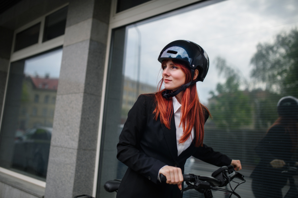 A portrait of businesswoman commuter on the way to work with bike, sustainable lifestyle concept.