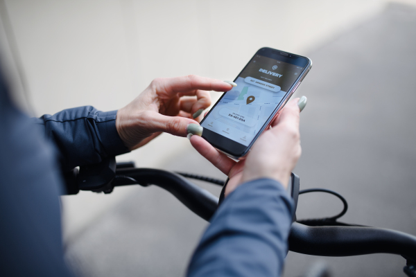 A courier riding a bicycle and looking on the cellphone asnd using delivery app, sustainable transport concept