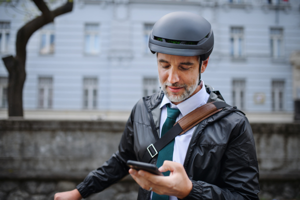 A portrait of businessman commuter on the way to work, pushing bike and calling on mobile phone, sustainable lifestyle concept.