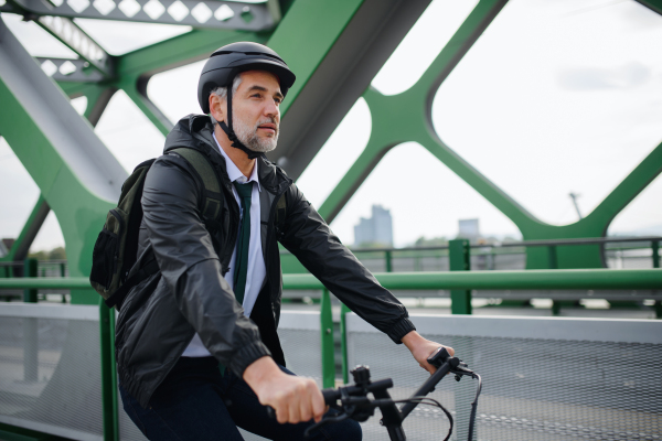 A businessman commuter on the way to work, riding bike over bridge, sustainable lifestyle concept.