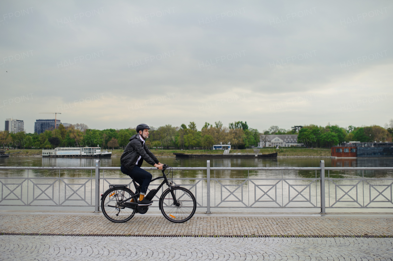 A businessman commuter on the way to work, riding bike onver bridge, sustainable lifestyle concept.