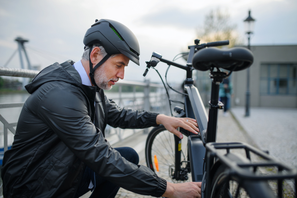 Portrait of businessman in the bicycle helmet fixing his bike, sustainable lifestyle concept.