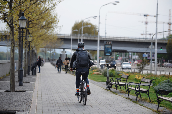 A businessman commuter on the way to work, riding bike in the street, sustainable lifestyle concept. Rear view.