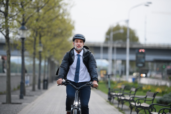 A businessman commuter on the way to work, riding bike in city, sustainable lifestyle concept.