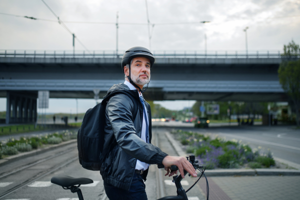 A businessman commuter on the way to work, crossing street with bike, sustainable lifestyle concept.