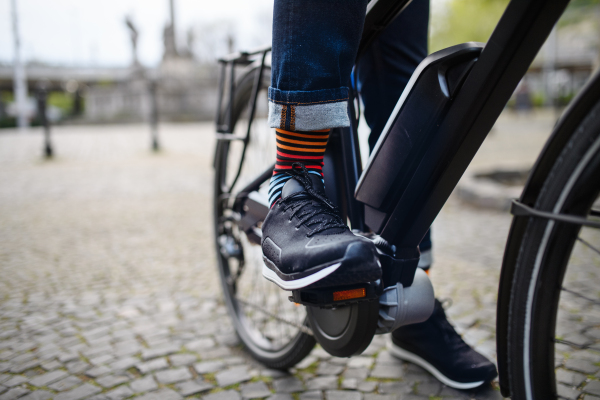 Businessman commuter on a way to work, close up of his legs riding bicycle.