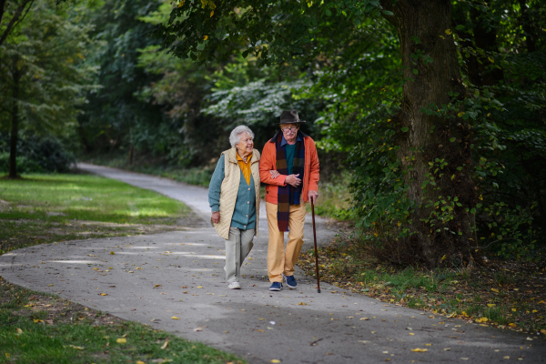 Happy senior couple in autumn clothes walking in park together.