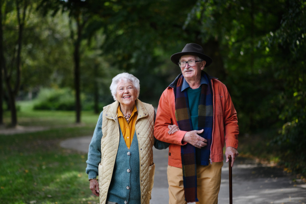 Happy senior couple in autumn clothes walking in park together.