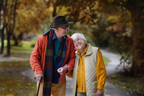 Happy senior couple in autumn clothes walking in park together.