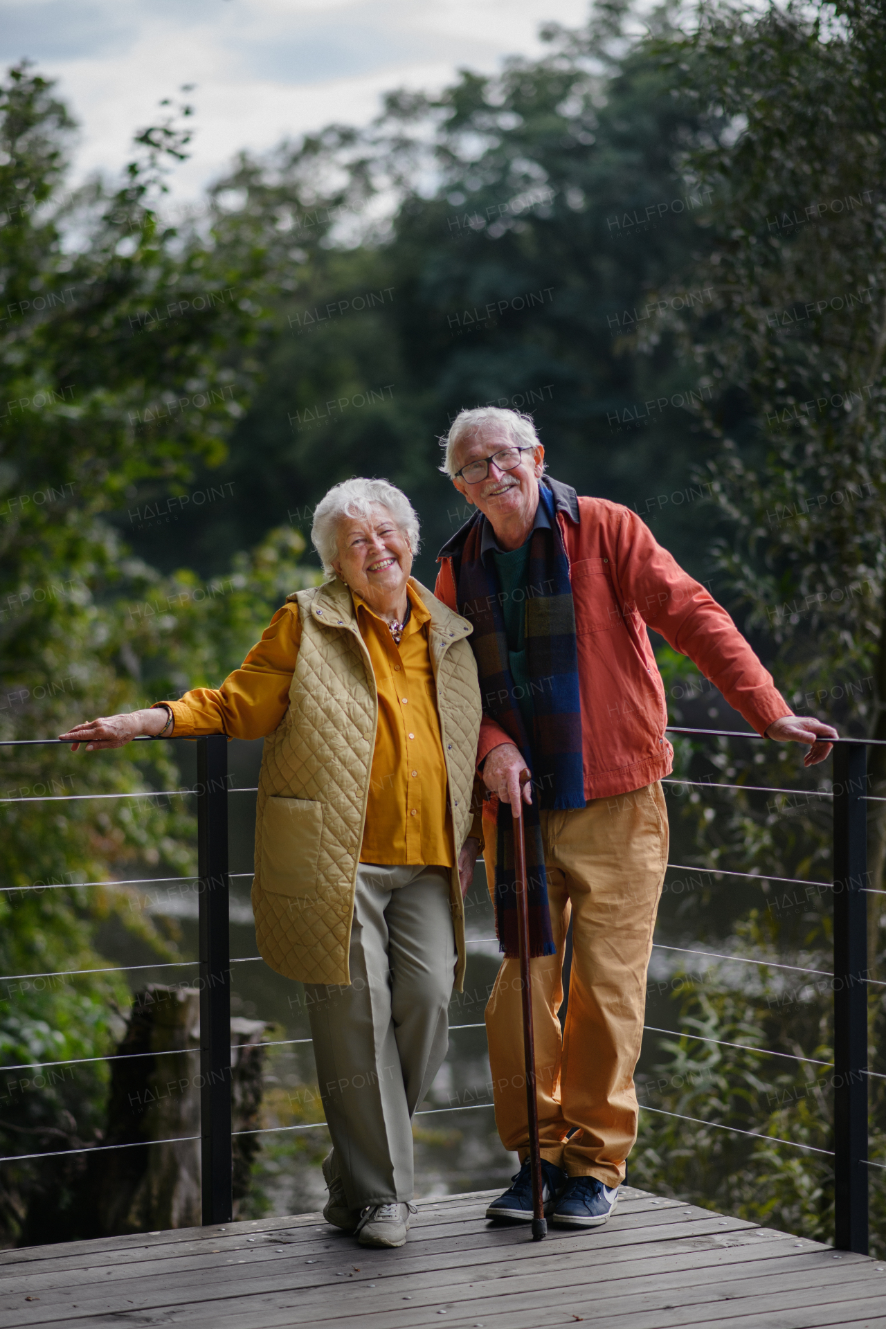 Happy senior couple at autumn walk near a lake, having break.