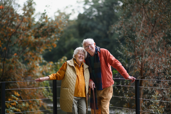 Happy senior couple at autumn walk near a lake, having break.