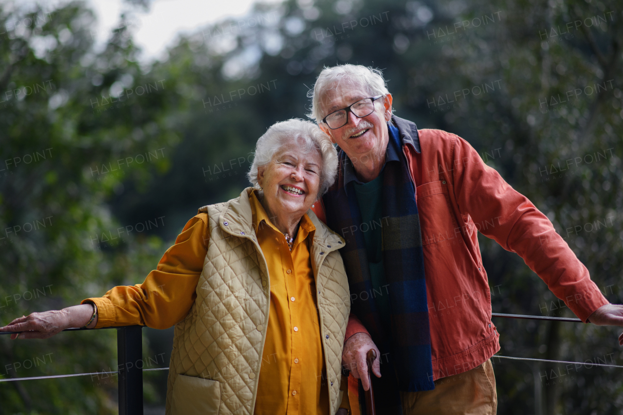 Happy senior couple at autumn walk near a lake, having break.