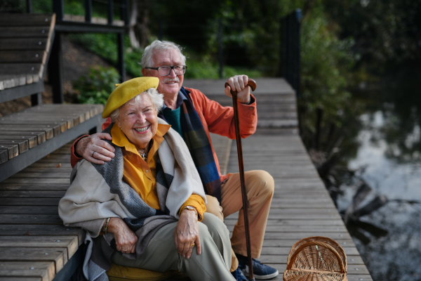 Happy senior couple resting near a lake after walk.