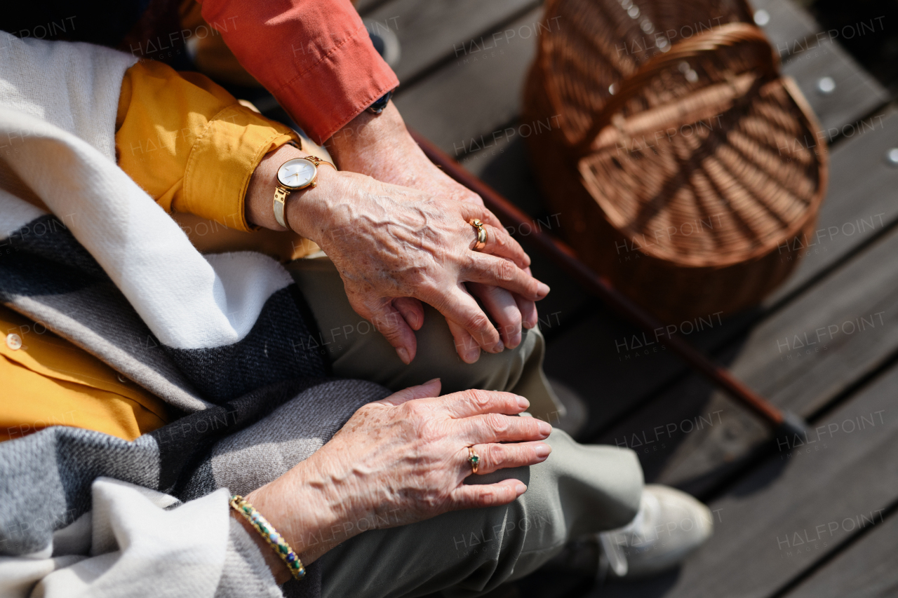 Top view of seniors holding hands, having a romantic moment during autumn picninc near lake.