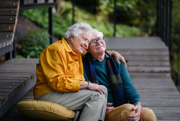 Happy senior couple resting near lake after autumn walk.