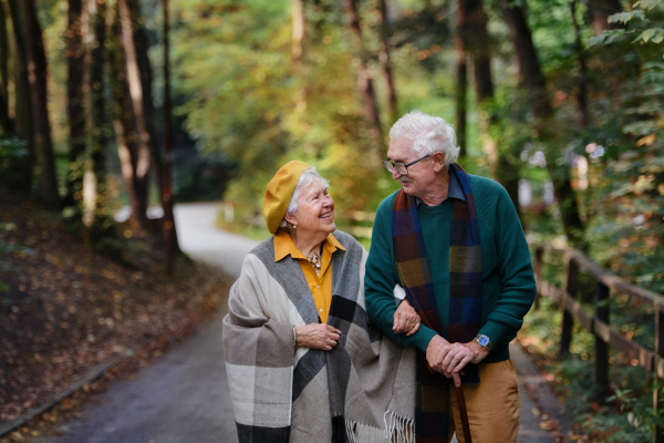 Happy senior couple in autumn clothes walking in park together.