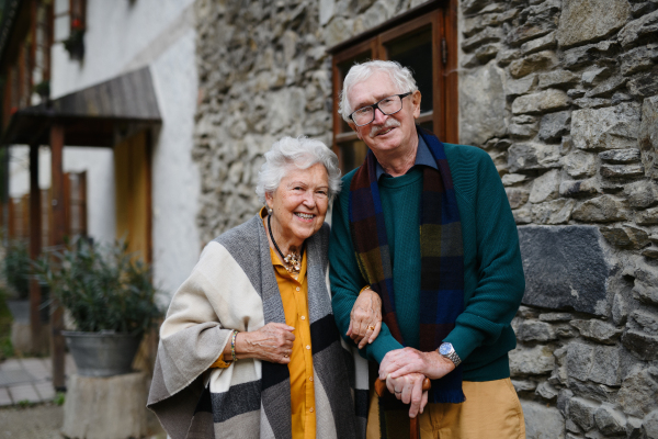 Happy senior couple posing near their old countryside house.