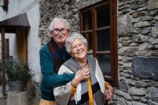 Happy senior couple posing near their old countryside house.