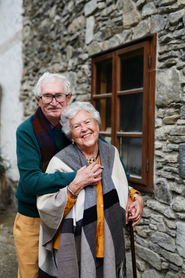 Happy senior couple posing near their old countryside house.