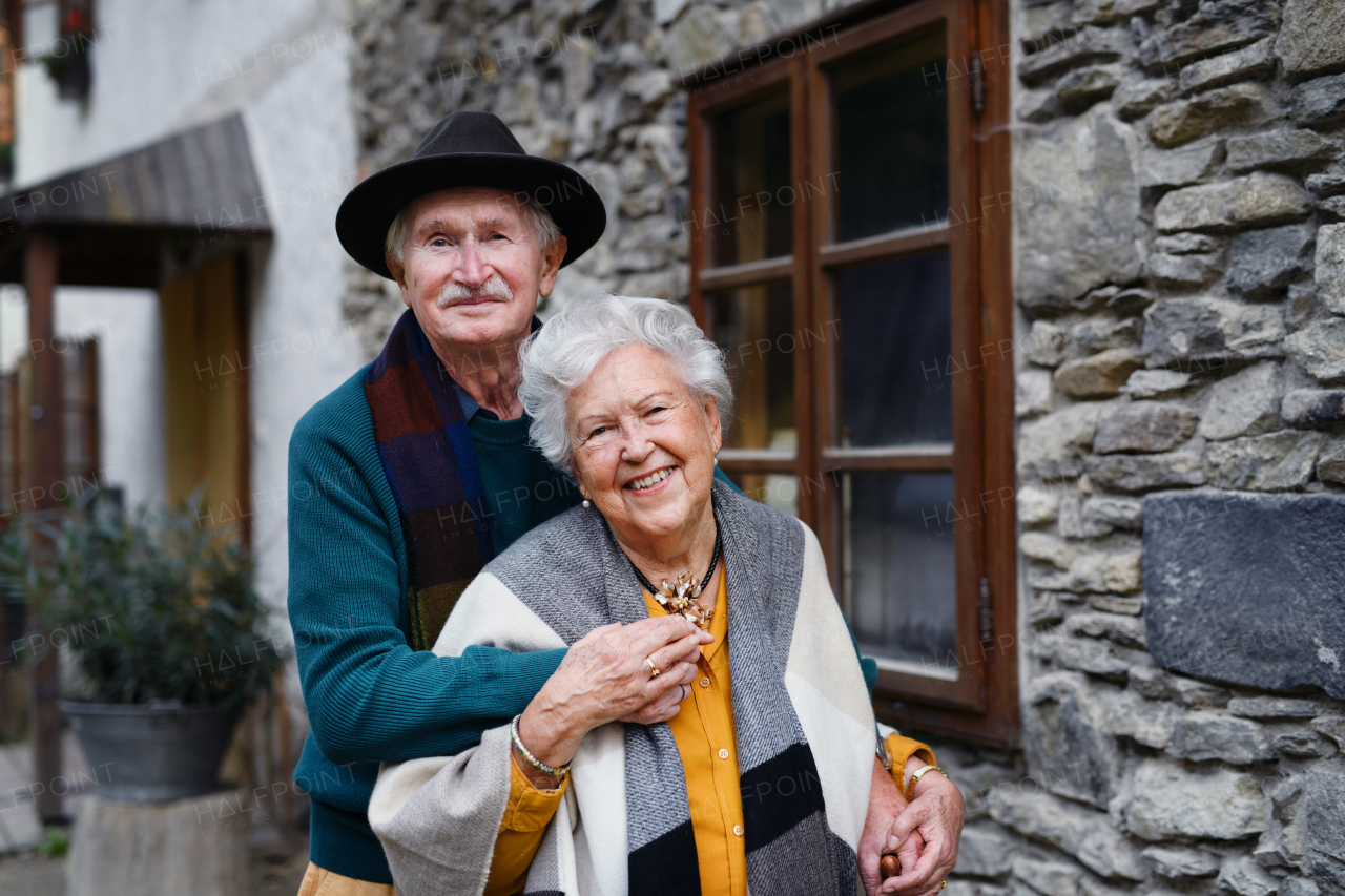 Happy senior couple posing near their old countryside house.