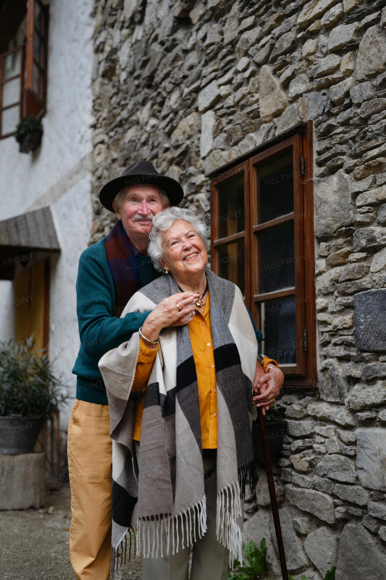 Happy senior couple posing near their old countryside house.