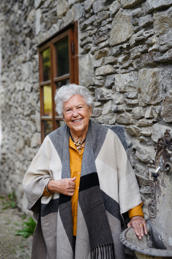 Portrait of elegant senior woman standying near to countryhouse.