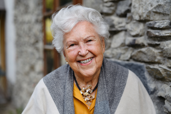 Portrait of elegant senior woman standying near to countryhouse.