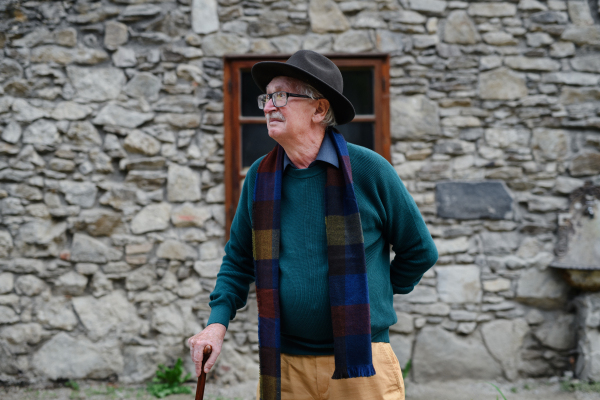 Portrait of senior man with black hat leaning of a house.