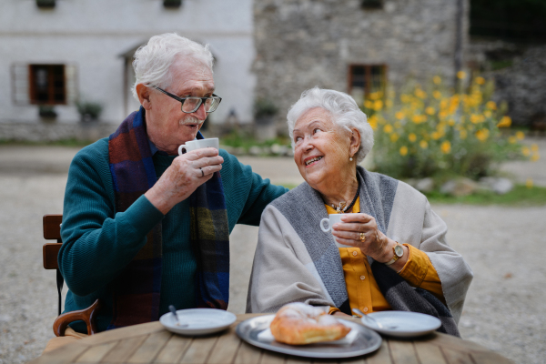 Senior couple enjoying cup of coffee and cake outdoor in a cafe.