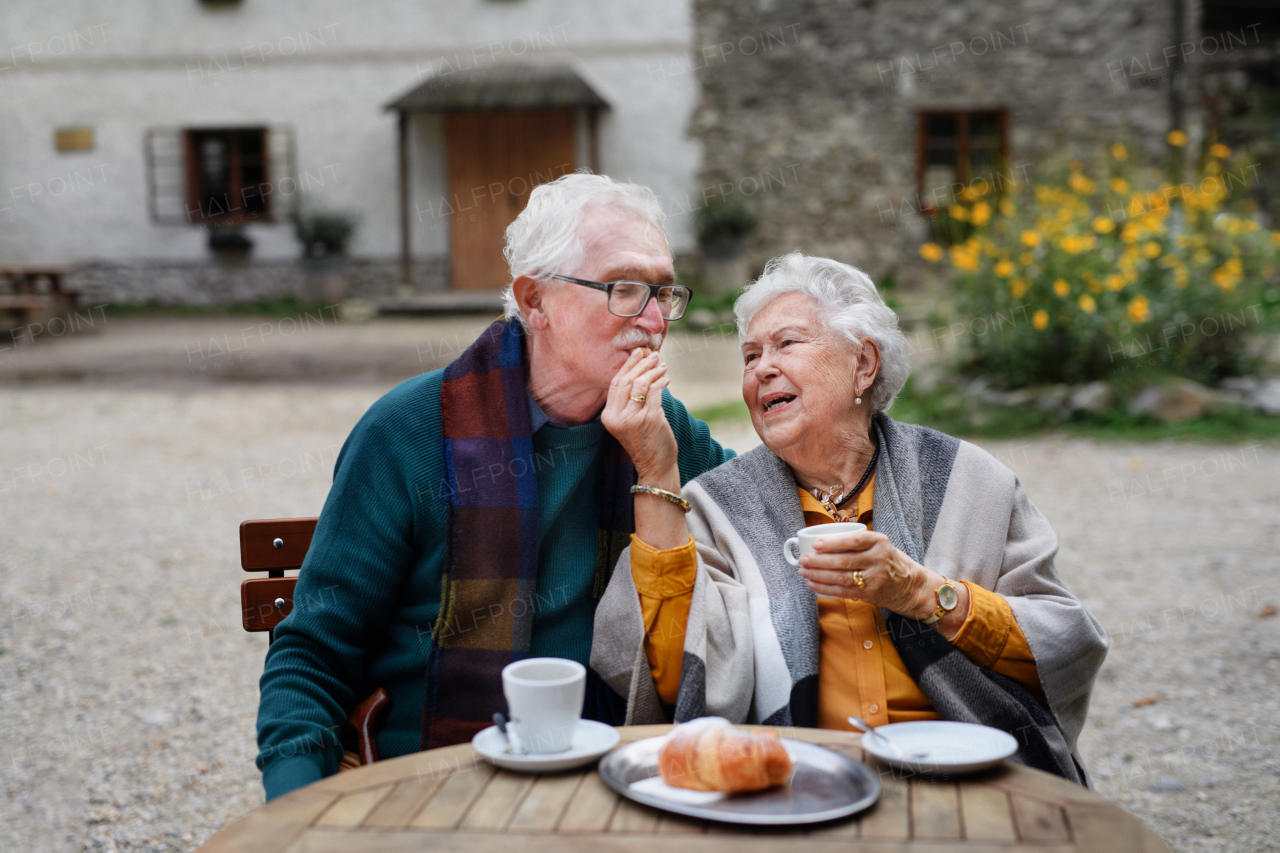 Senior couple enjoying cup of coffee and cake outdoor in a cafe.