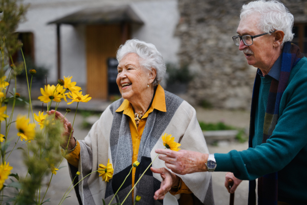 Happy senior couple at autumn city walk, posing with the flowers.