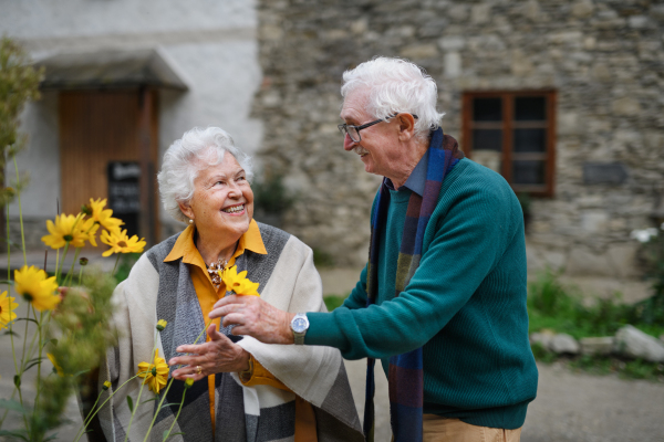 Happy senior couple at autumn city walk, posing with the flowers.