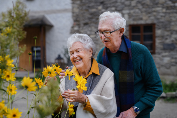 Happy senior couple at autumn city walk, posing with the flowers.