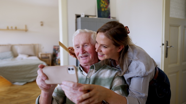 Video of daughter visiting her senior father and taking a selfie with him.