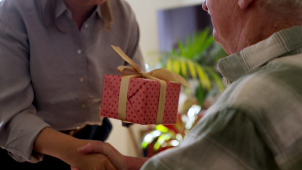 Daughter giving a gift to her senior father.