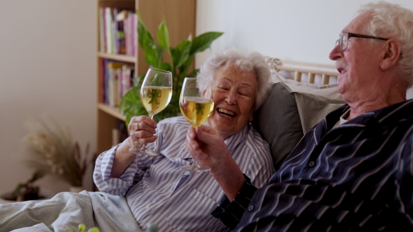 Video of senior couple enjoying breakfast in a bed with a glass of wine. Senior couple in love.