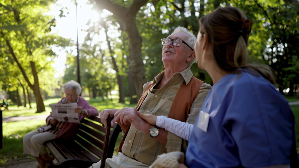 Video of a nurse on a walk in a public park with patients, resting on bench.