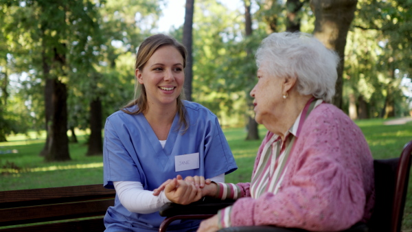 Video of a nurse on a walk in a public park with patients, resting on bench.