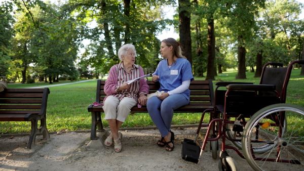 Video of a nurse on a walk in a public park with patients, resting on bench.