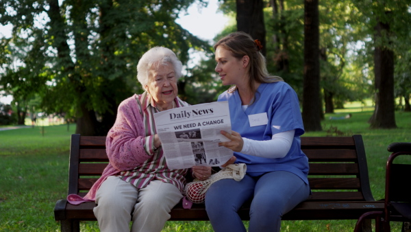 Video of a nurse on a walk in a public park with patients, resting on bench.