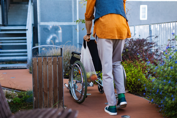 Elderly man pushing his own wheelchair. Wheelchair for support and balance for senior with walking difficulty, mobility aid.