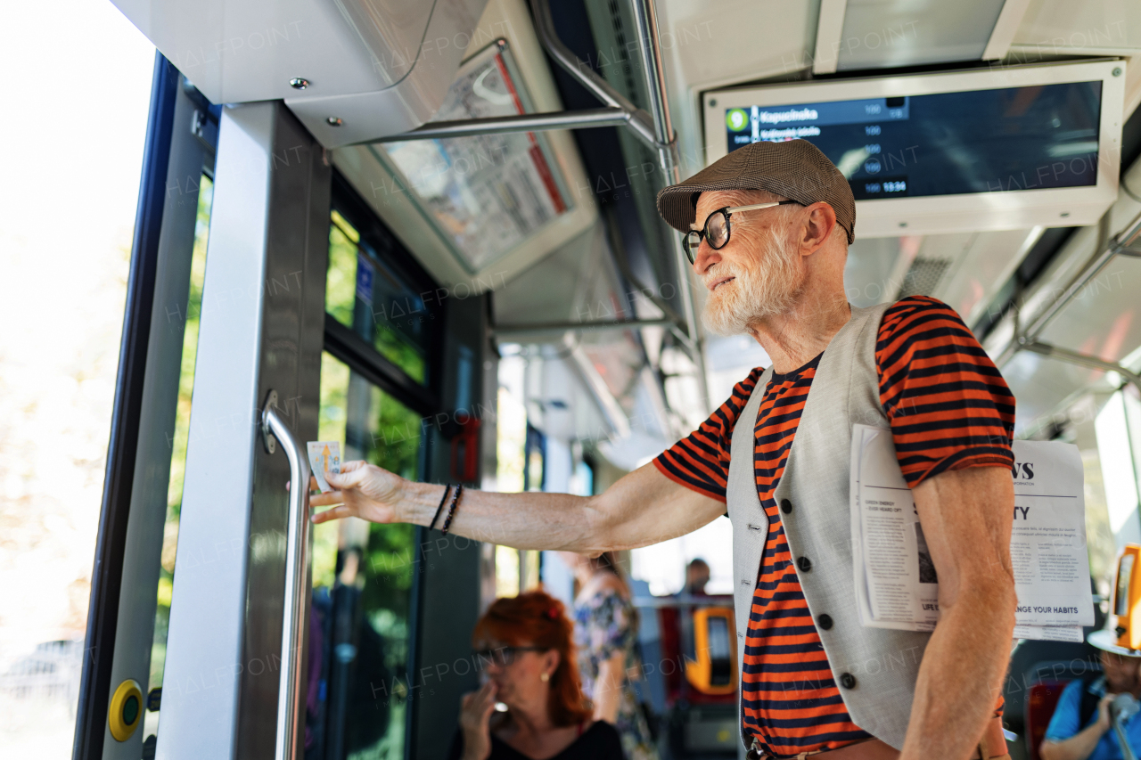 Elderly man traveling through the city by bus, standing by door. Senior city commuter taking tram to grocery store, using public transportation.