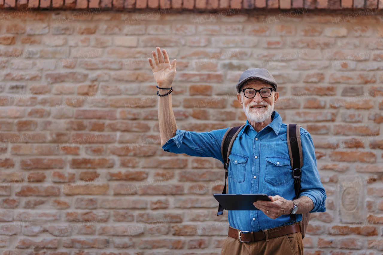 Side view of senior tourist exploring a new city, interesting places. Elderly man holding tablet, looking for the route. Traveling and solo trips in retirement.