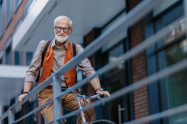 An elderly man, cyclist traveling through the city by bike, Senior city commuter riding a bike.