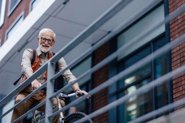 An elderly man, cyclist traveling through the city by bike. Senior city commuter riding a bike to grocery store.