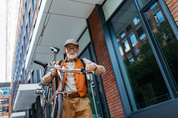 An elderly man, cyclist traveling through the city by bike, carrying bicycle on shoulder. Senior city commuter riding a bike.