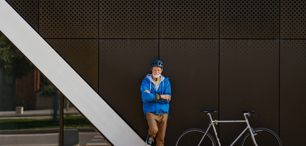 Banner of elderly man, cyclist traveling through the city by bike. Vital senior city commuter riding a bike, exercising. Banner with copy space.