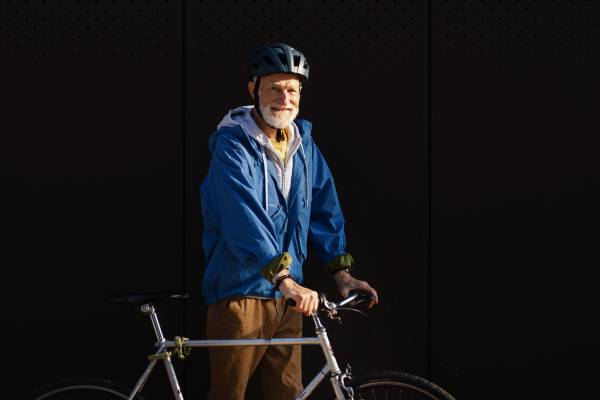 An elderly man, cyclist traveling through the city by bike. Vital senior city commuter riding a bike, exercising.