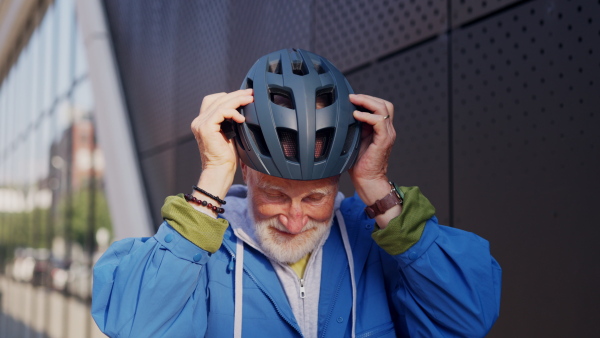 An elderly man, cyclist getting ready to travel through the city by bike. Vital senior city commuter riding a bike, exercising.